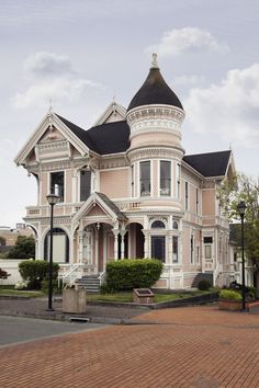 a large pink house with a black roof and white trim on the top floor, in front of a street light