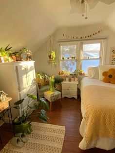 a bed room with a neatly made bed and lots of plants on the windowsill