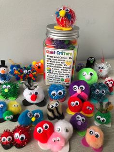 a jar filled with lots of different colored stuffed animals next to each other on top of a table