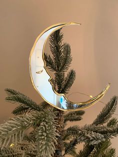 a christmas tree with a gold crescent decoration on it's side and a mirror in the middle