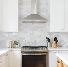 a stove top oven sitting inside of a kitchen next to white cupboards and drawers