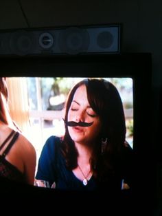 a woman with fake moustaches on her face in front of a tv