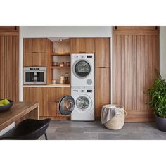 a washer and dryer sitting in a kitchen next to a table with fruit on it