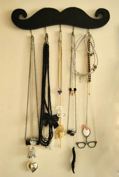 a wall mounted shelf with many necklaces and eyeglasses hanging from it's sides