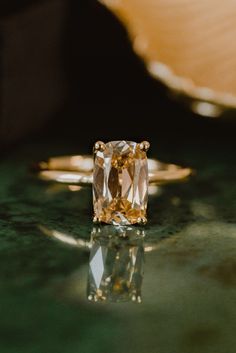 an orange and white diamond ring sitting on top of a green surface