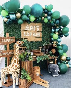 a giraffe statue sitting next to a display of fake plants and balloons in the shape of animals