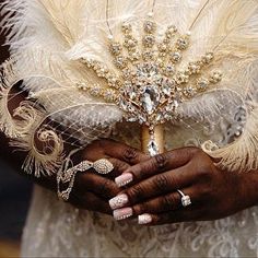 a close up of a person holding a piece of jewelry and a feather headdress