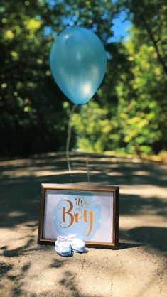 a blue balloon is in the air next to a sign that says it's a boy