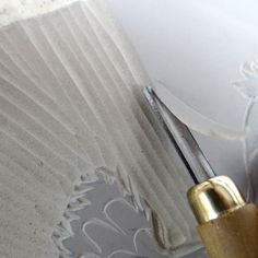 a close up of a person using a brush to paint a wall with white paper