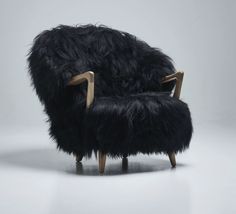 a chair made out of black fur with wooden legs and arm rests on a white background