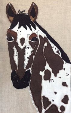 a close up of a horse's head on a piece of cloth with brown and white paint