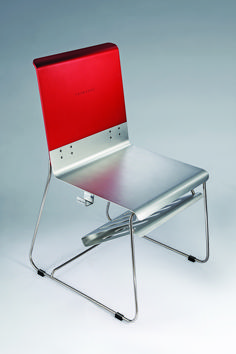 a metal chair with a red seat and back rests against a gray background, while the rest of the chair is empty