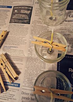 several wooden clothes pins are placed on top of newspaper pages and next to some glass jars