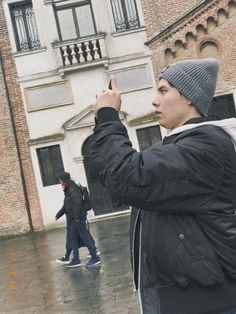 a man taking a photo with his cell phone in front of a building on a rainy day