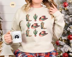 Celebrate the magic of the season with our Western Christmas Sweatshirt!  This retro-inspired, sand-colored crew neck features an adorable design of cowboy boots, cacti, and festive hats, perfect for adding a touch of the Wild West to your holiday attire. Whether it's for a family holiday gathering or as a thoughtful festive holiday gift, this Christmas sweatshirt is ideal for matching pajamas or your "my first Christmas" moments. Popular right now, it's a must-have for anyone who loves combining holiday cheer with western charm. Get cozy in style and join the Christmas crew with this unique holiday staple! #HolidayPajamas #FestiveHolidayGift #FamilyPajamas #PopularRightNow #ChristmasSweatshirt #MatchingPajamas #WesternShirt #MyFirstChristmas #ChristmasCrewNeck #HowdyShirt #RetroChristmas Christmas Cacti, Cactus Sweatshirt, Matching Christmas Shirts, Holiday Attire, Western Christmas, Holiday Pajamas, Matching Family Pajamas, Matching Pajamas, Family Pajamas