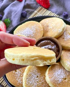 a person holding a cookie in front of some pancakes