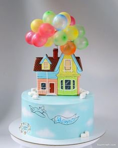 a birthday cake with a house and balloons on top