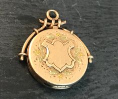 "A victorian multi-gold (tested 10k or better) shield, aesthetic locket.  Condition for its age-I see no problems, closes tight, good hinge.  Size  1\" in length, wt 3.6 grams.  The round locket is hand engraved with green gold leaves surrounding the raised and unmonogramed shield center.  Interesting top half wire design.  monogramed on back imaged.  Circa late 1800s.," Antique Gold Locket Necklace With Charms, Gold Antique Locket Necklace With Charms, Historical Gold Medallion Jewelry, Victorian 14k Gold Locket Necklace, Antique Yellow Gold Locket Necklace With Charms, Victorian Locket Necklace Stamped 14k, Shield Aesthetic, Victorian Antique Gold Oval Locket Necklace, Victorian Rose Gold Locket Necklace