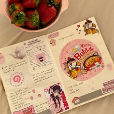 a bowl of strawberries next to a recipe book with stickers on the pages