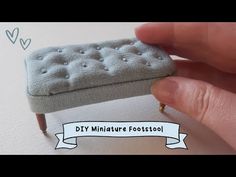 someone is holding a miniature footstool made out of fabric and wood legs, with the word diy miniature footstool on it