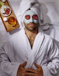 a man in a bathrobe with his face covered by a towel and some food