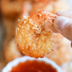 a person holding up a fried food item with dipping sauce in the bowl behind them