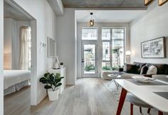 a living room filled with furniture next to a white wall and wooden floored walls