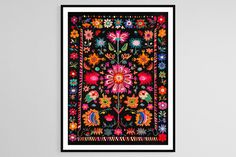 an art print with colorful flowers and leaves on black paper, hanging on a wall