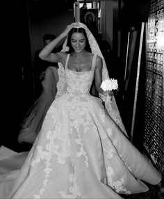 a woman in a wedding dress and veil walking down the aisle with her hand on her head