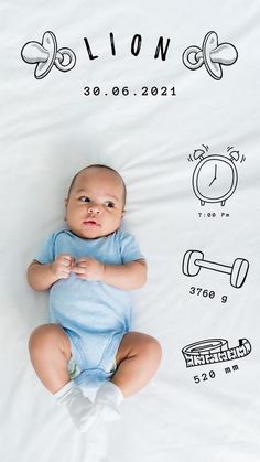 a baby laying on top of a bed next to an alarm clock wall decal