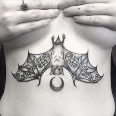 a woman's stomach with a bat tattoo on her belly and the moon above it