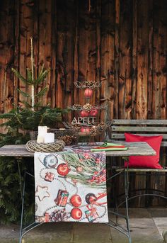 a table and bench with christmas decorations on it in front of a wooden fenced area