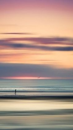 a person walking on the beach at sunset