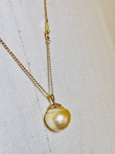 14k Gold Natural Large 14mm Golden South Sea Tahitian Pearl Drop.  This large sized genuine seawater pearl exhibits excellent luster, thick nacre, radiant & smooth surface with some minor natural spots.  Attached to a fancy style 14k gold 7mm x 5mm pearl bail. Shown with an 18.5 inch rolo style 14k gold necklace. Can be removed from this chain and added to any necklace up to 5mm.  Weight with chain 5.7 grams If you are interested in a different chain please message me. I have several types and sizes of 14k gold or 18k gold chains. It helps to take a ruler and use the measurements as a comparison. Item's pictures are enlarged and zoomed-in close to show the fine details in item/s in the listings. If you have any other questions about this listing or any of my other listings please ask and I Elegant Shell-shaped Pearl Drop Necklace, Gold Pearl Necklace With High Luster Round Pendant, Elegant Gold Shell Necklace With Pearl Charm, Classic High Luster Pendant Pearl Necklace, Yellow Gold Pearl Necklace With High Luster Baroque Pearls, Yellow Gold Pearl Pendant Necklace With High Luster, Yellow Gold High Luster Pearl Pendant Necklace, Yellow Gold High Luster Baroque Pearl Necklace, Gold Tahitian Pearl Necklace