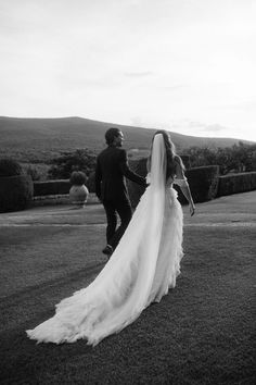 a bride and groom walking in the grass