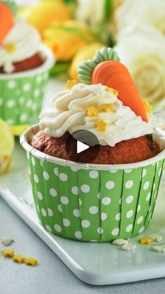 cupcakes in green polka dot paper cups with carrots on top and white frosting