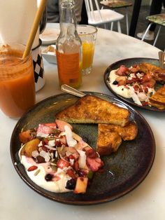 two plates filled with food sitting on top of a table next to cups and glasses