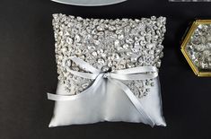 a white pillow with silver sequins on it next to a plate and knife