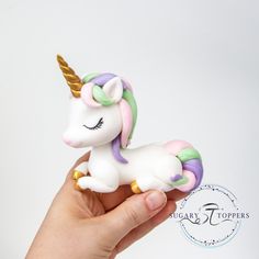 a hand is holding a small toy unicorn