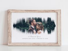 a wooden frame with a photo of a couple and trees in the background on a white wall