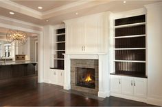 an empty living room with a fireplace and built in bookshelves