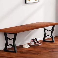 two pairs of shoes sitting on the floor next to a wooden bench in front of a white wall