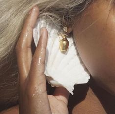 a close up of a person holding a seashell in front of their face and ear