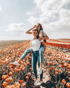 two girls in a field of orange tulips, one holding the other on her back