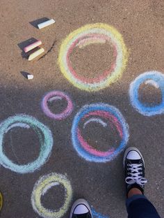 someone standing in front of chalk circles on the ground with crayons around them