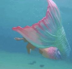 an underwater view of a mermaid swimming in the ocean with her tail spread out and wings outstretched