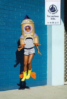 a person in a costume is standing next to a blue wall