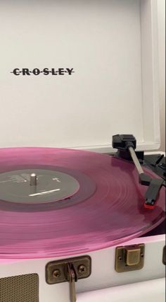 a pink record player with the word crossley on it's side in front of a white box