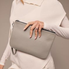 a woman is holding a gray purse