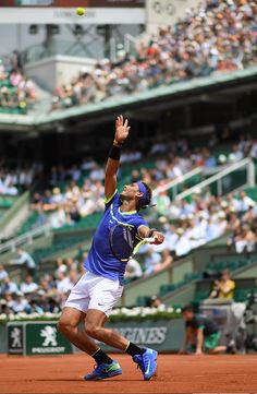 a tennis player is reaching up to hit the ball with his racket in front of an audience